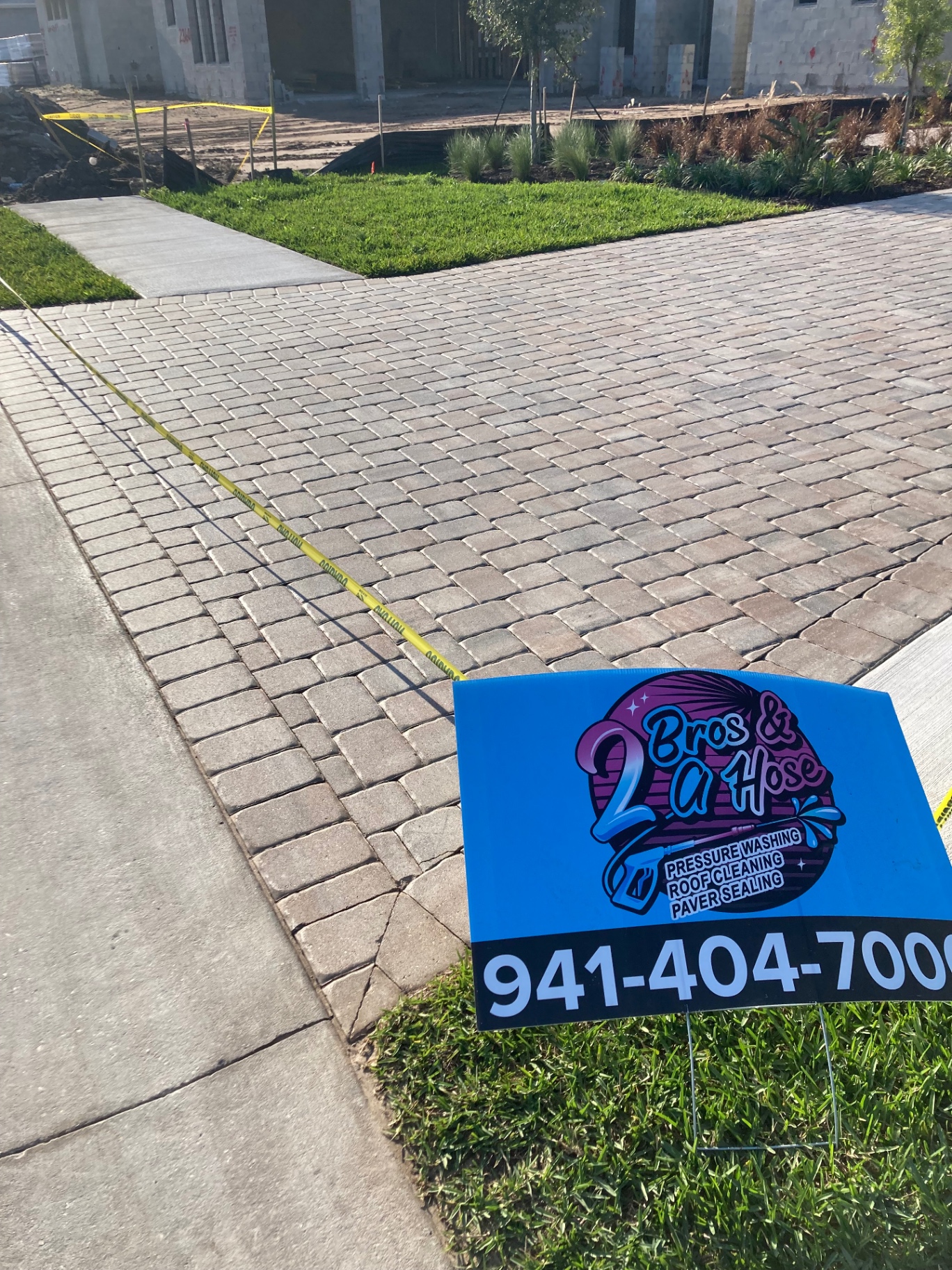 Cleaned new-construction paver driveway with 2 Bros & A Hose yard sign in Azario Esplanade
